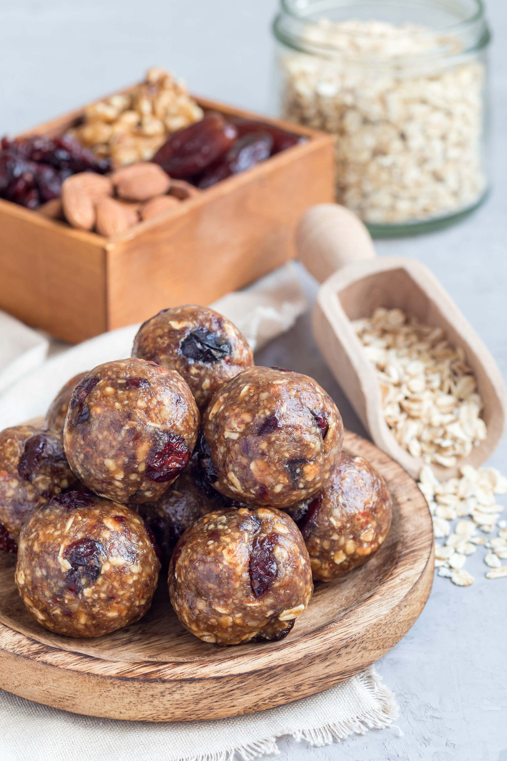 Healthy energy balls with cranberries, nuts, dates and rolled oats on wooden plate, vertical
